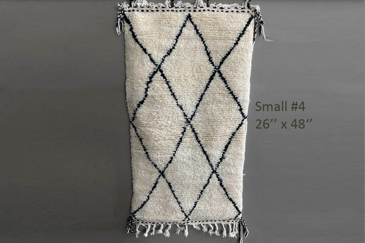 Cream wool rug with black diamond pattern and fringe ends, 26" x 48".