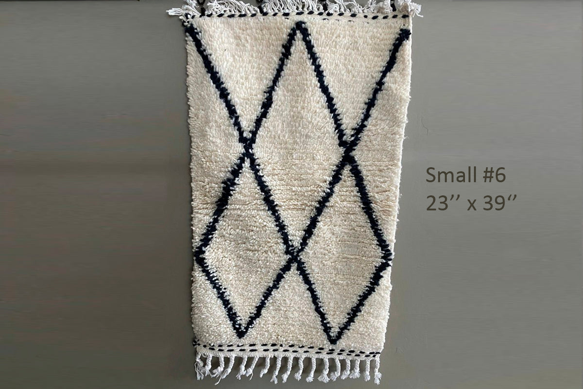 Cream wool rug with black diamond pattern and fringe trim, 23" x 39".