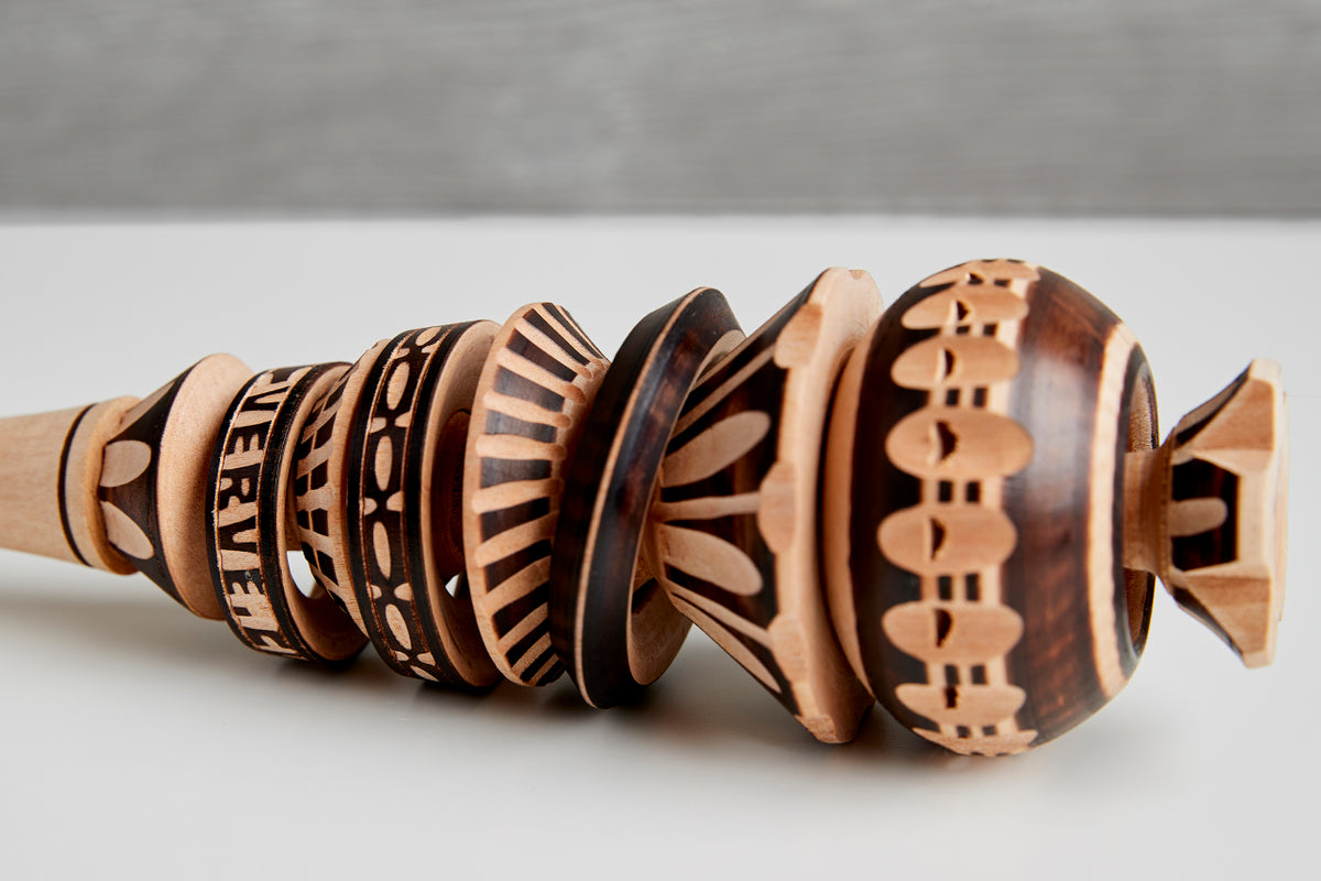 Wooden molinillo whisk with carved geometric patterns and decorative bands along the handle and bulbous head.