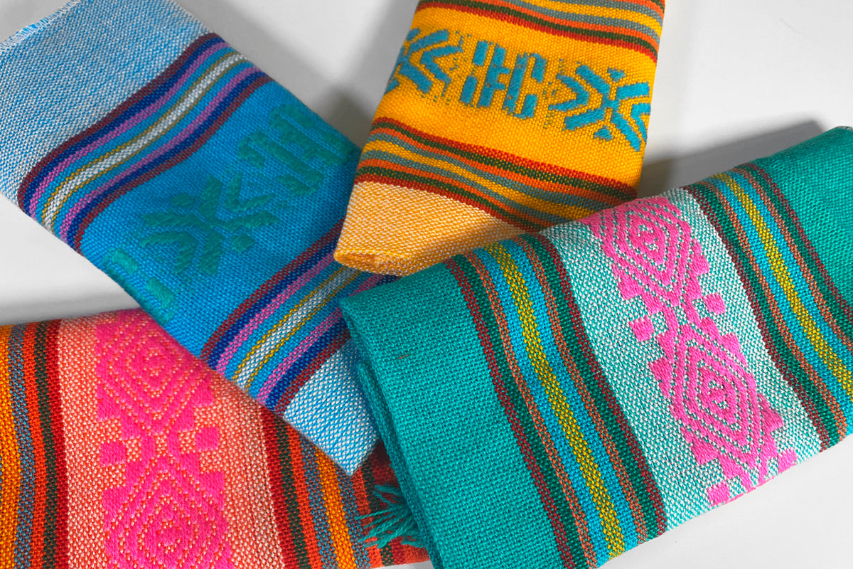 Five colorful woven coasters with geometric patterns in blue, orange, pink, and teal stripes.