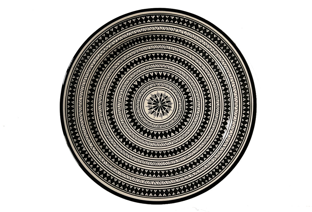 Round ceramic platter with concentric geometric patterns in black and cream, featuring a central star motif.