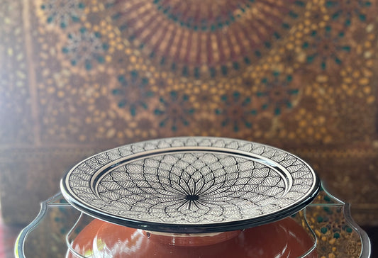 Ceramic platter with blue and white geometric patterns and decorative border, displayed against ornate gold and teal patterne