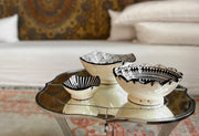 Three cream ceramic bowls with black geometric patterns nested together on a metal tray.