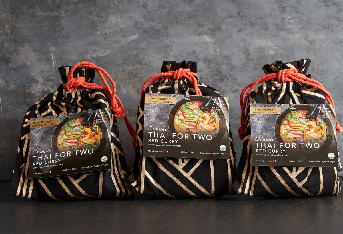Three black pouches with tan stripe pattern and red cord drawstrings, each containing organic red curry kit with labeled fron