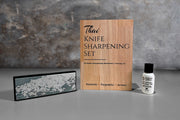 Thai knife sharpening set with wooden box, whetstone, and honing oil bottle displayed together.