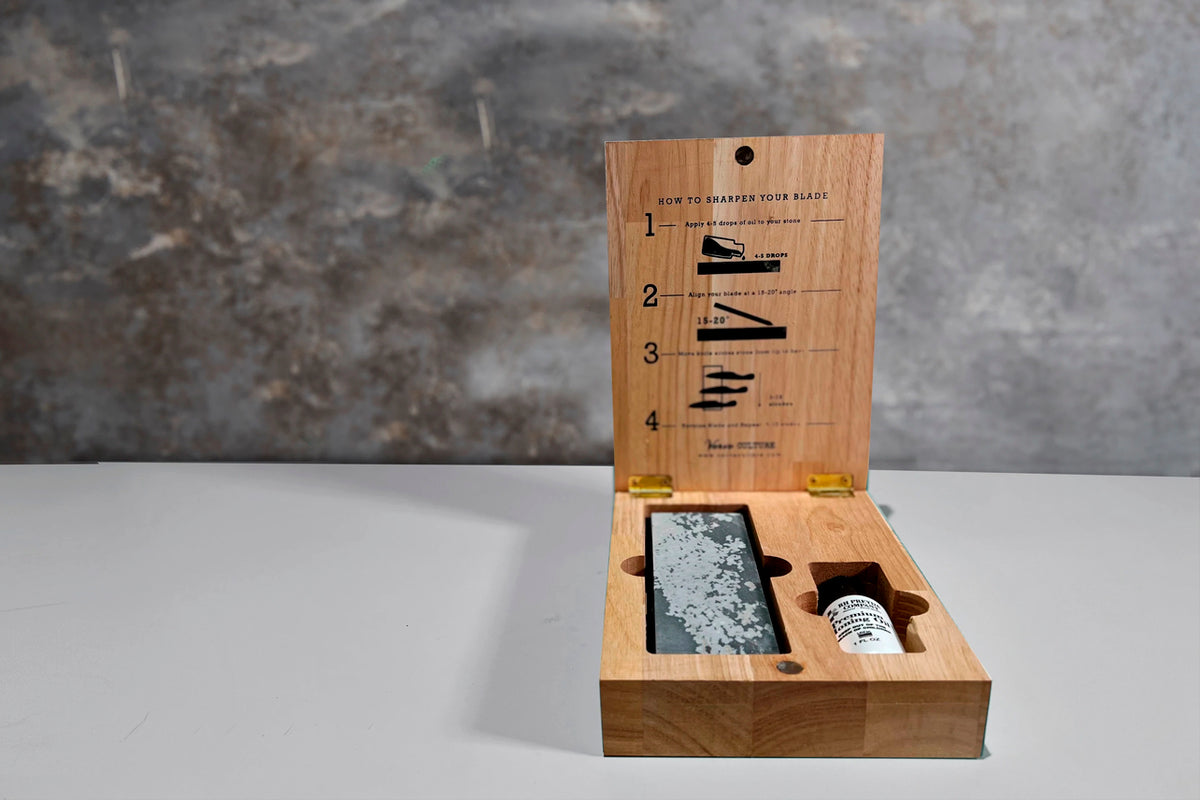 Wooden sharpening kit with stone, oil bottle, and instruction guide showing four sharpening techniques.