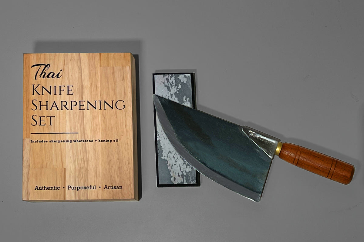 Thai Knife Sharpening Set with wooden box, sharpening whetstone, and wooden-handled knife on gray background.