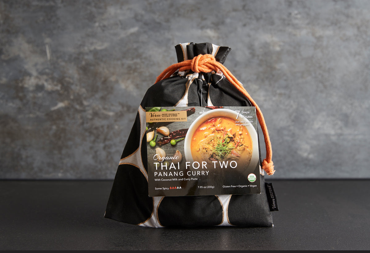 Organic Panang Curry Kit package inside black cloth drawstring bag with orange cord tie on gray background.