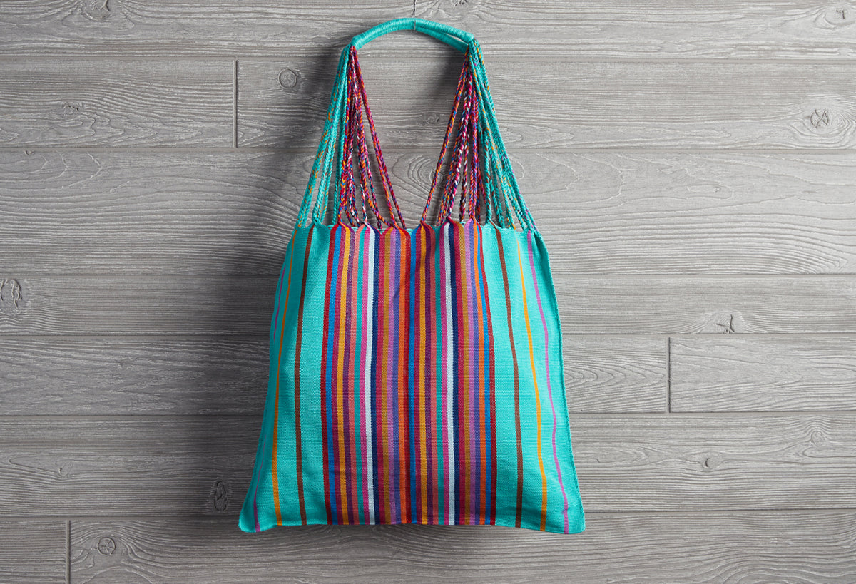 Woven tote bag with turquoise handles and multicolored vertical stripes in red, blue, orange, and yellow.